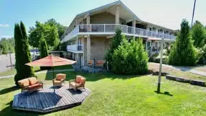 A two-story motel with outdoor seating, surrounded by greenery and trees. The Bruce Anchor Motel sign is visible.